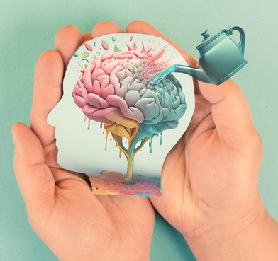 Hands holding paper head, human brain with flowers, self care and mental health concept, positive thinking, creative mind