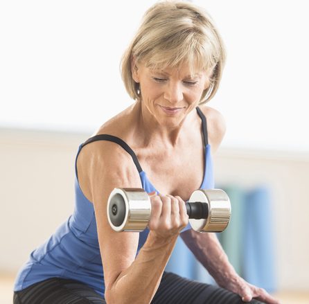 Mature Woman Lifting Dumbbell At Home