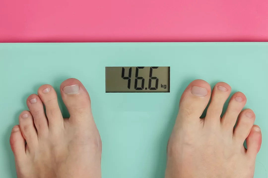 a woman's feet standing on weighting bathroom scales to check her weight